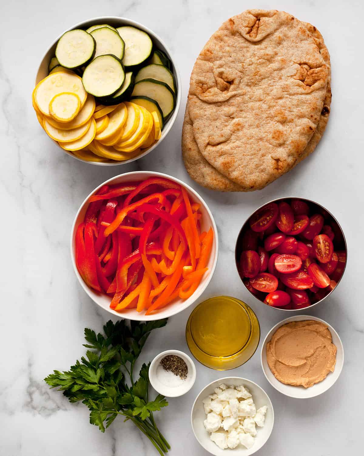 Ingredients including naan, vegetables, hummus and olive oil.