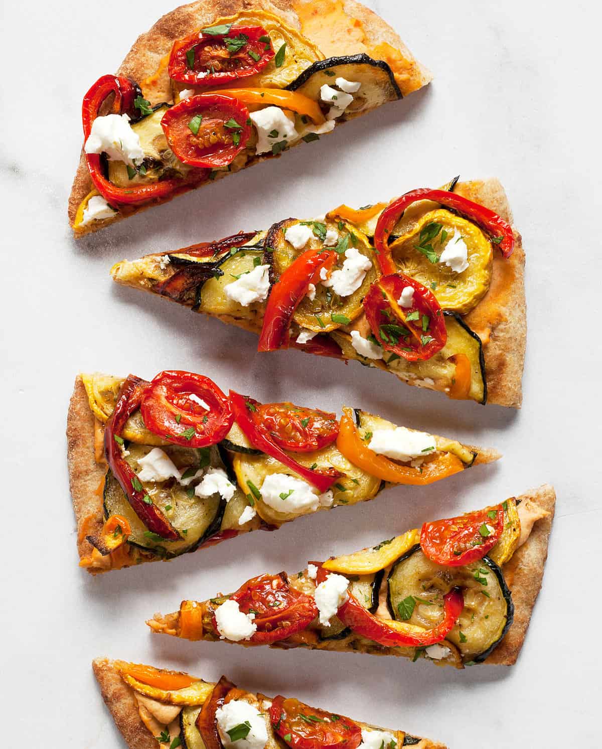 Sliced of naan flatbread topped with roasted vegetables and feta.