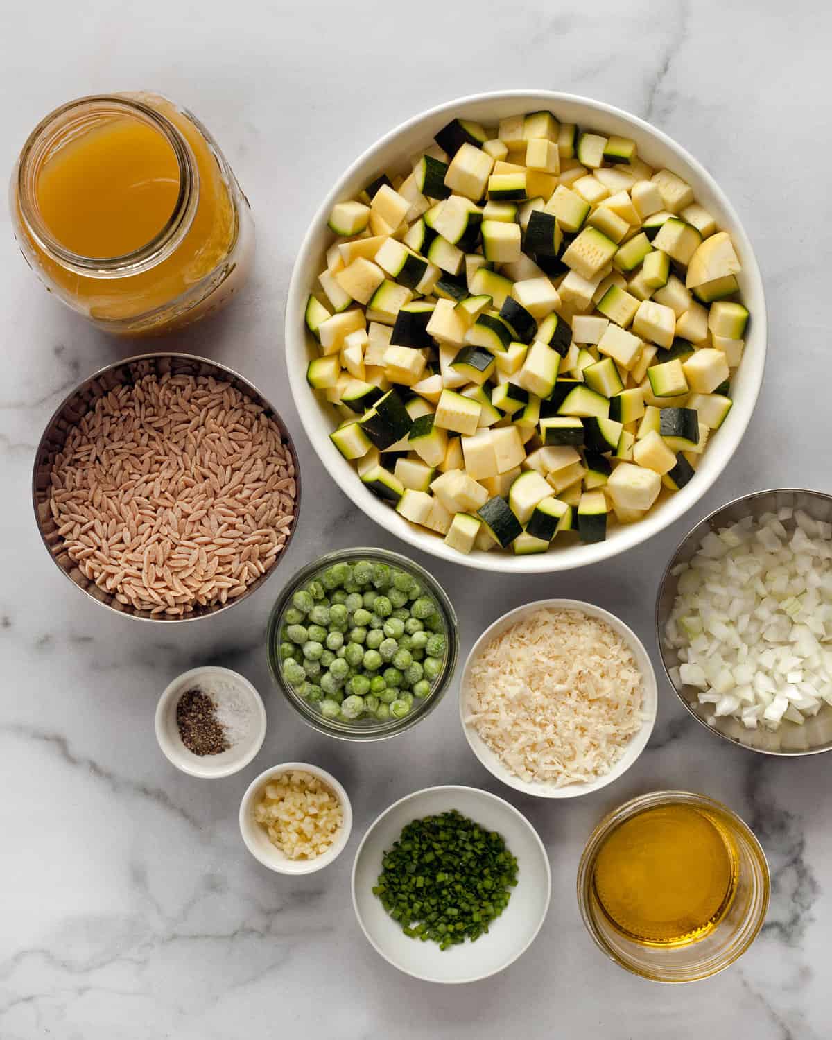 Ingredients including orzo, squash, zucchini, peas, parmesan, onions, garlic and vegetable broth.