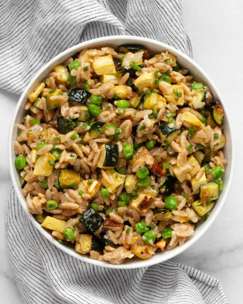 Parmesan orzo with squash and zucchini in bowl.