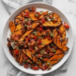 Sweet potatoes topped with pico de gallo on a plate.