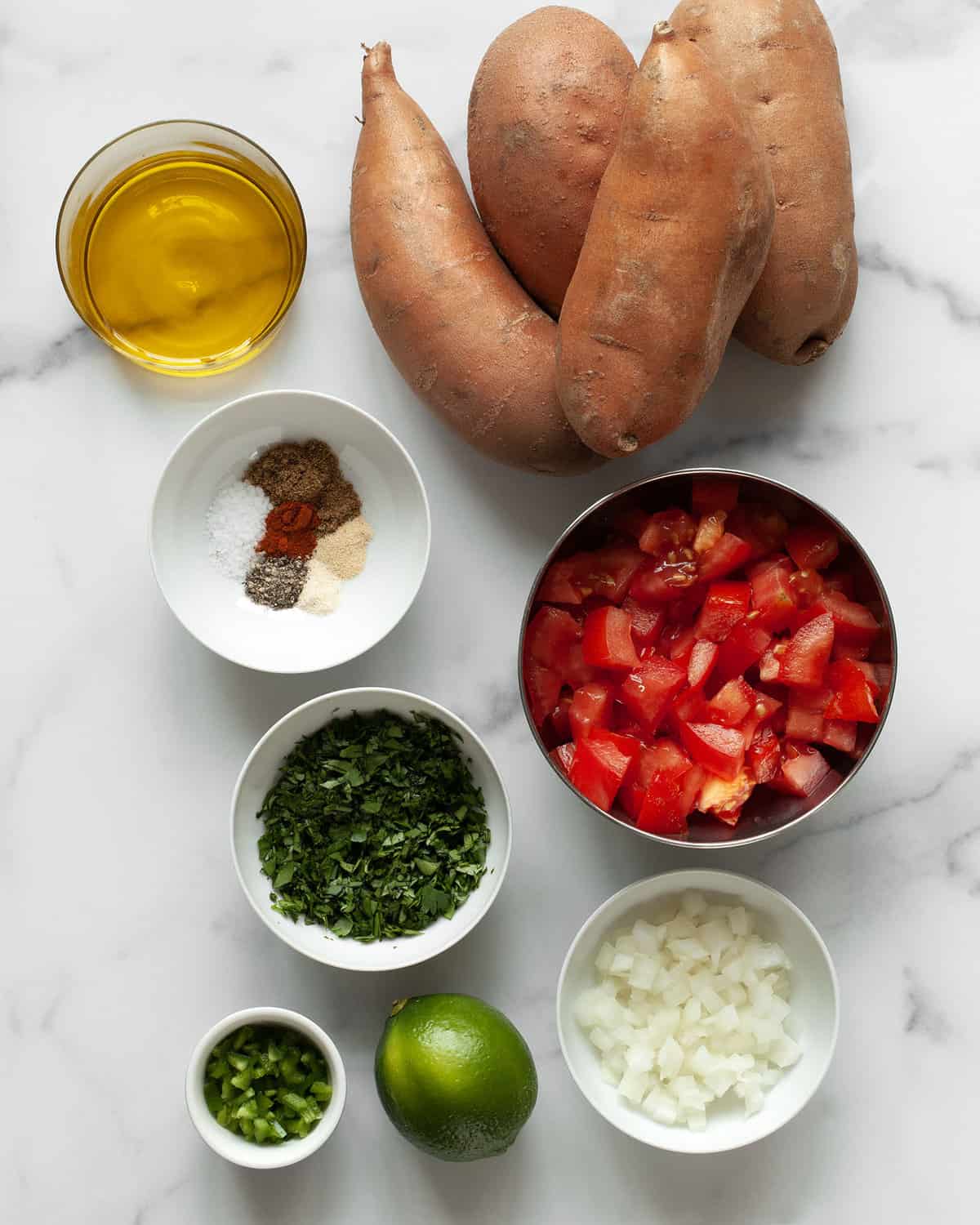 Ingredients including sweet potatoes, spices, oil, tomatoes, onions, jalapeños, lime and cilantro.