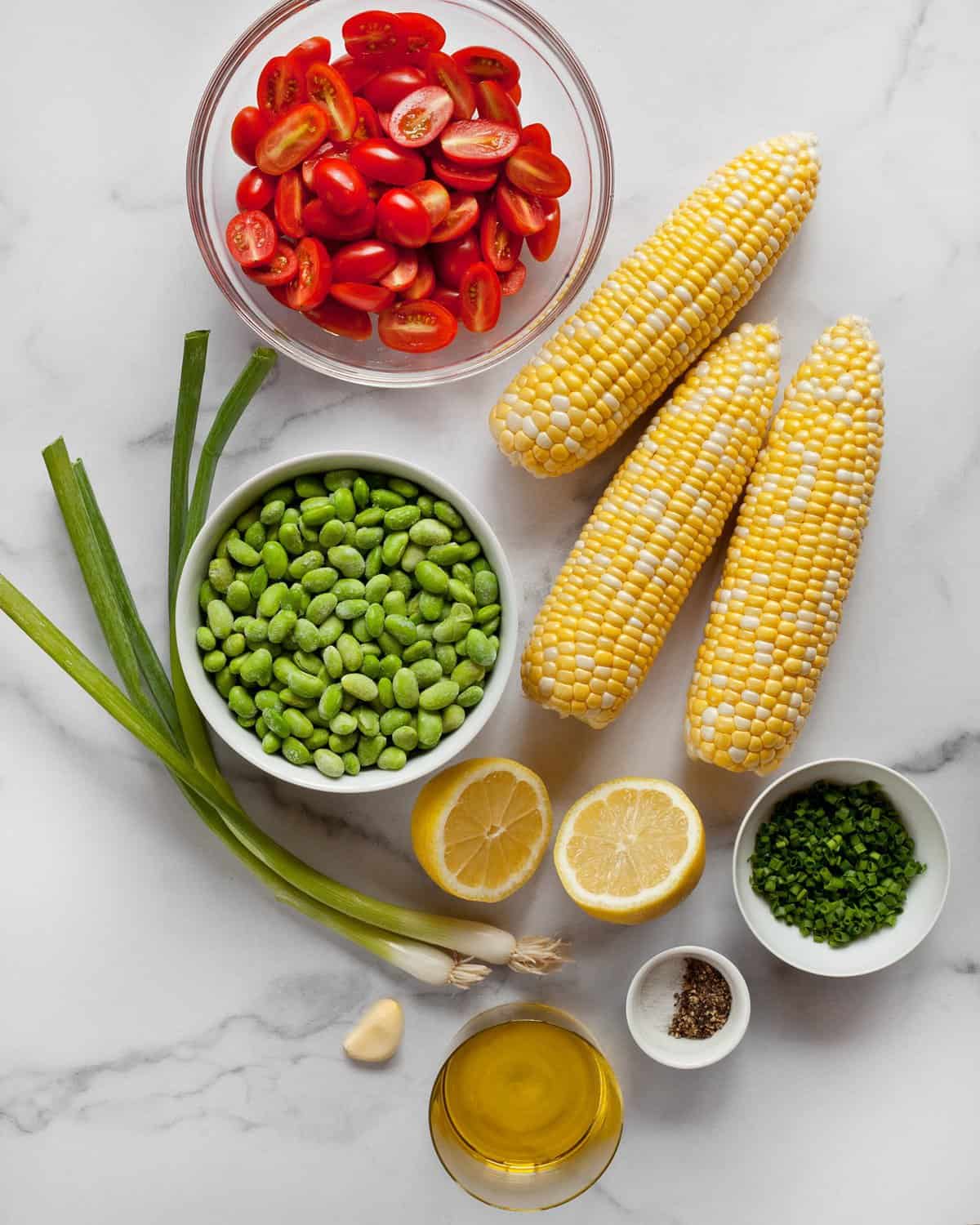 Ingredients including corn, edamame, tomatoes, scallions, lemon and chives.
