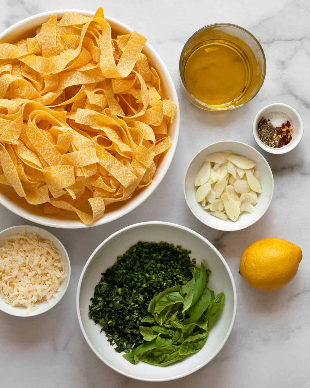 Ingredients including pasta, olive oil, lemon, herbs, garlic and parmesan cheese.