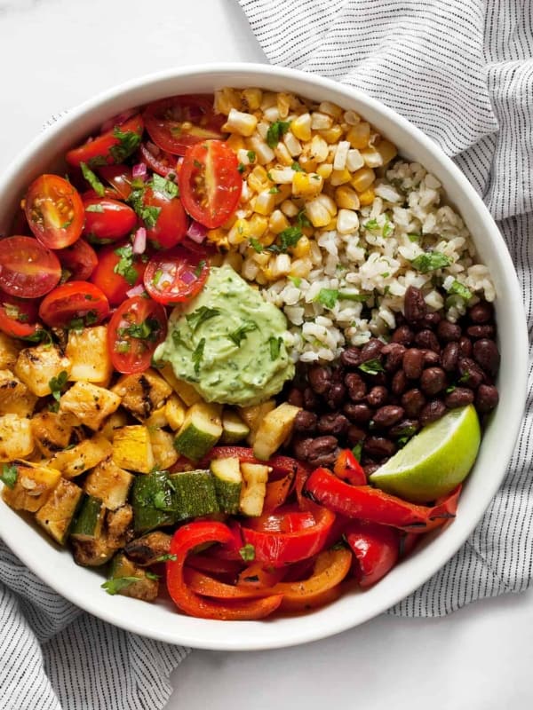 Assembled grilled veggie burrito bowl with squash, zucchini, peppers, black beans and pico de gallo.