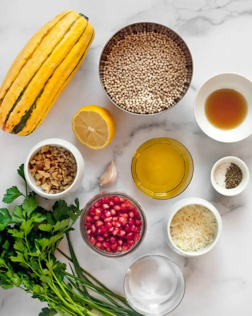 Ingredients including delicata squash, couscous, pomegranate seeds, parsley and walnuts,