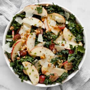 Apple salad with kale, grapes and walnuts in a bowl.