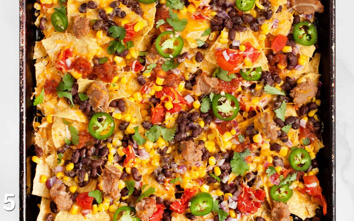 Assembled nachos on a sheet pan.