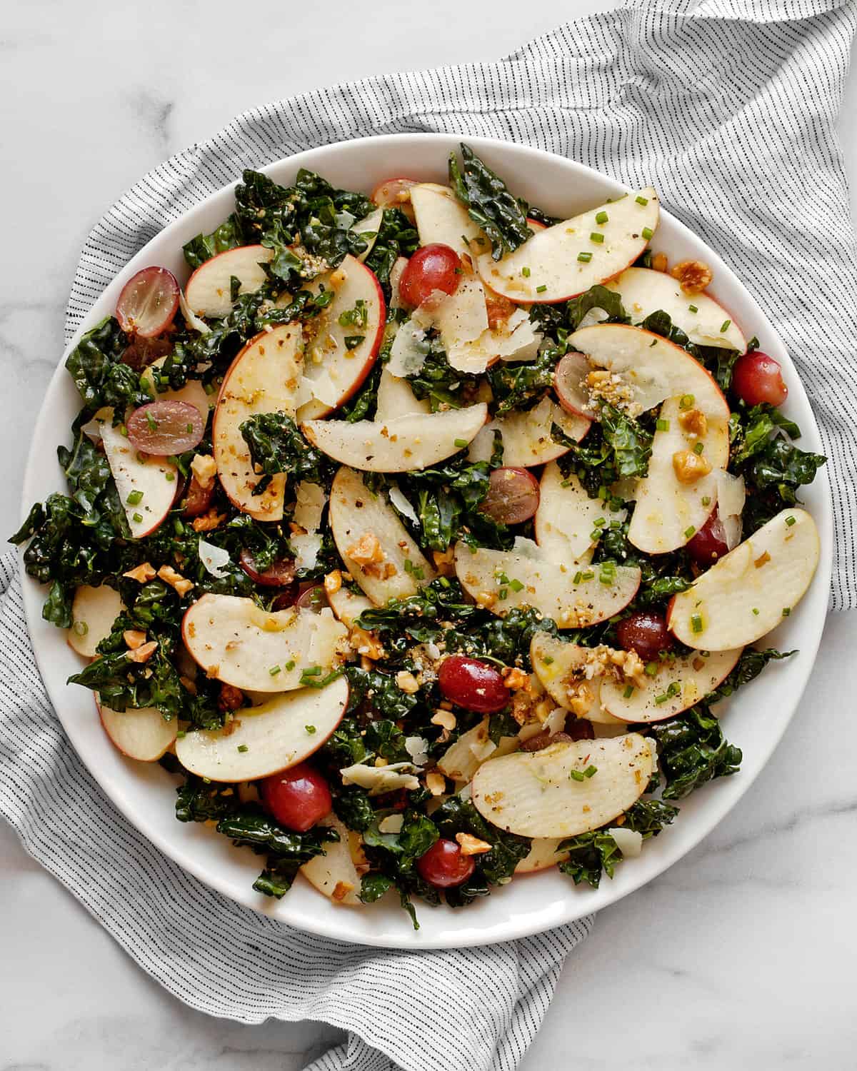 Kale salad with apples, grapes and walnuts on a plate.