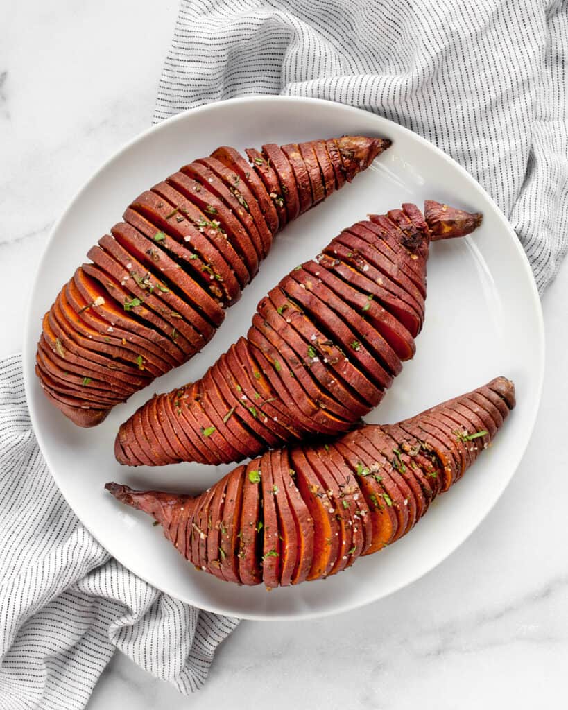 3 hasselback sweet potatoes on plate.