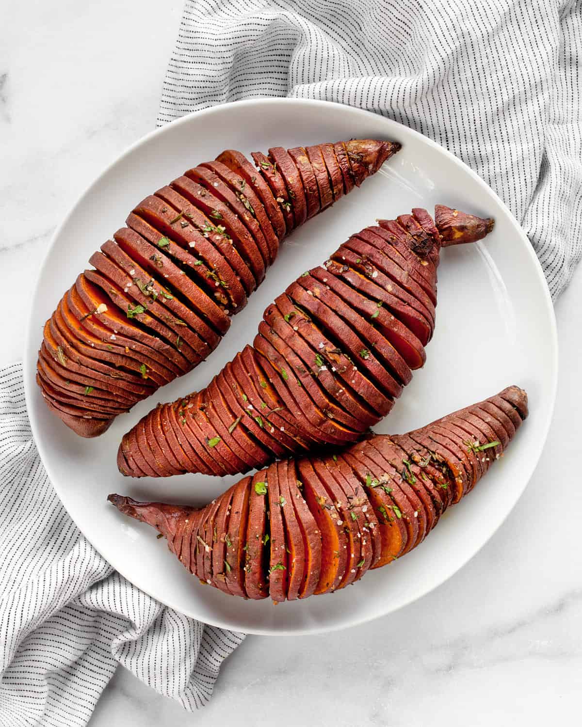 3 hasselback sweet potatoes on plate.