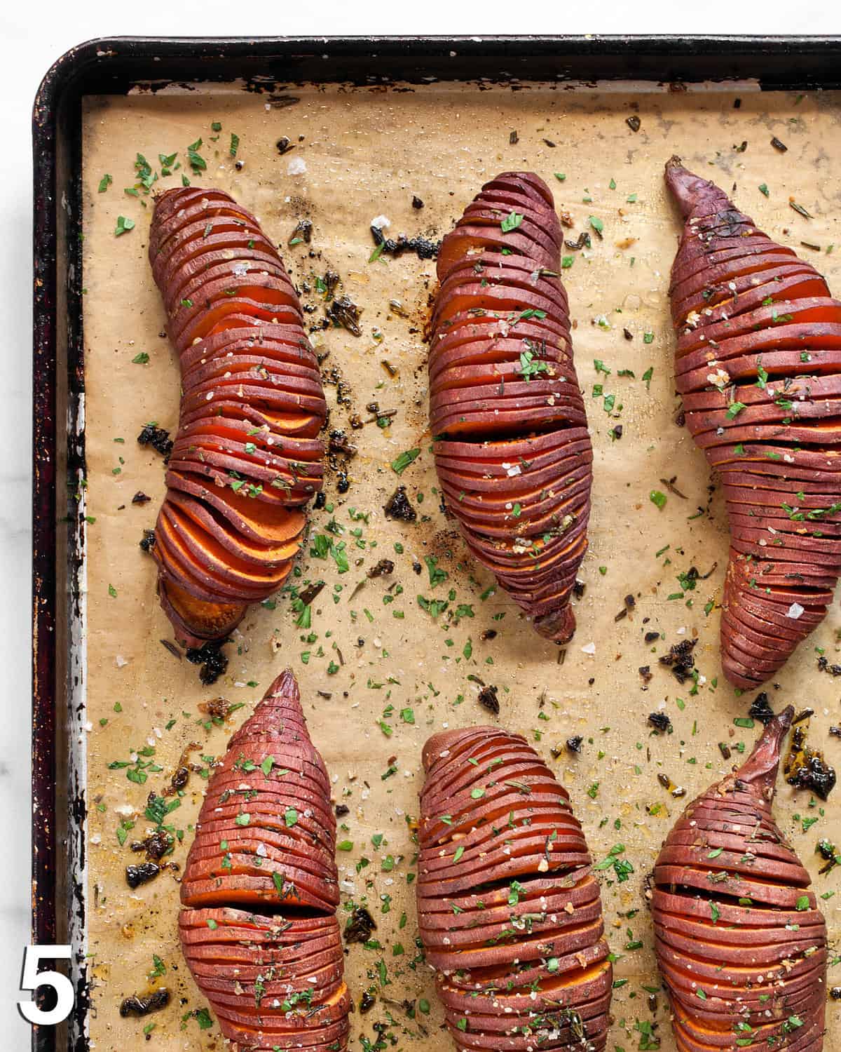 Baked hasselback potatoes on a sheet pan.