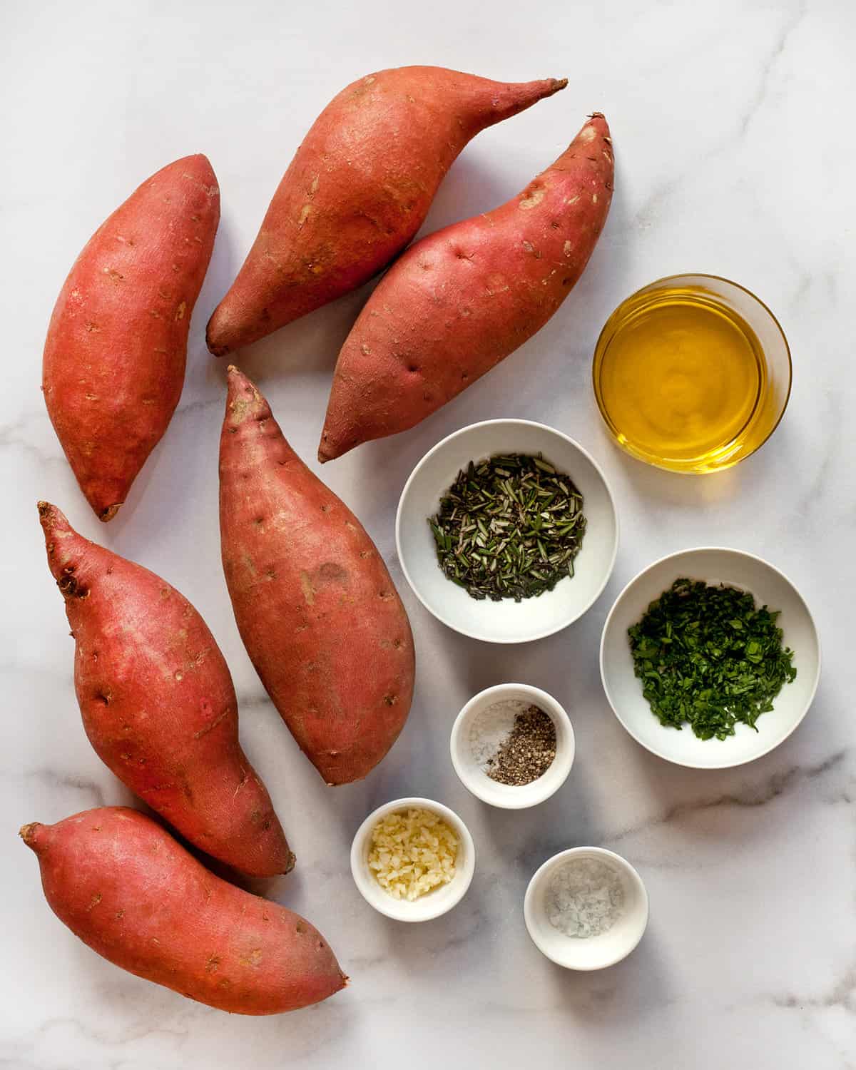 Ingredients including sweet potatoes, olive oil, rosemary, parsley, garlic, salt and pepper.