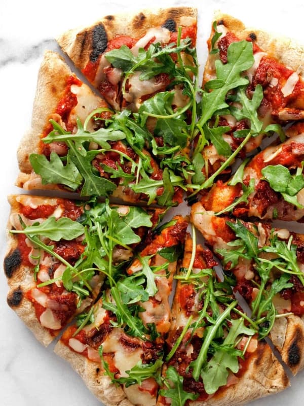 Arugula Pizza with Sun Dried Tomatoes cut into slices.