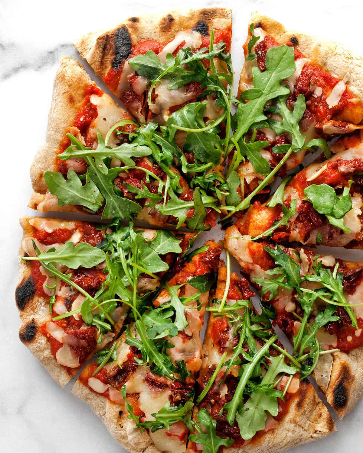 Arugula Pizza with Sun Dried Tomatoes cut into slices.