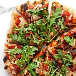 Arugula Pizza with Sun Dried Tomatoes cut into slices.