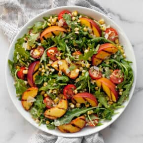 Grilled peach salad with corn on a plate.