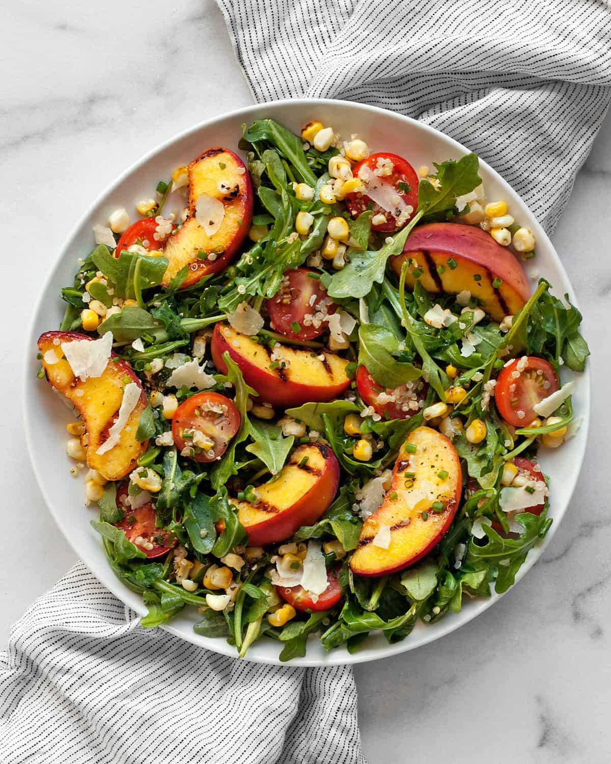 Grilled peach salad with corn on a plate.