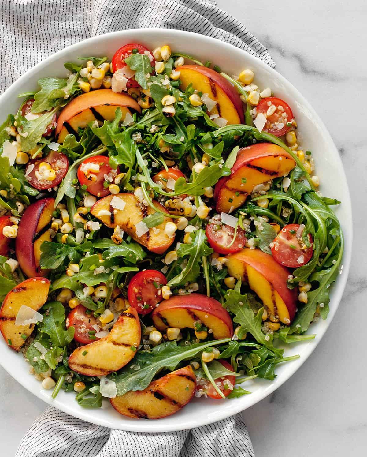 Grilled peach salad with corn on a plate.