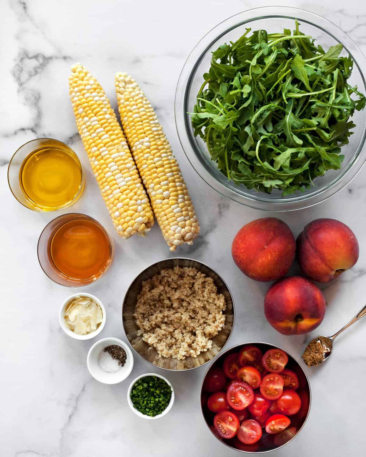 Ingredients including corn, peaches, arugula, olive oil, vinegar and quinoa.