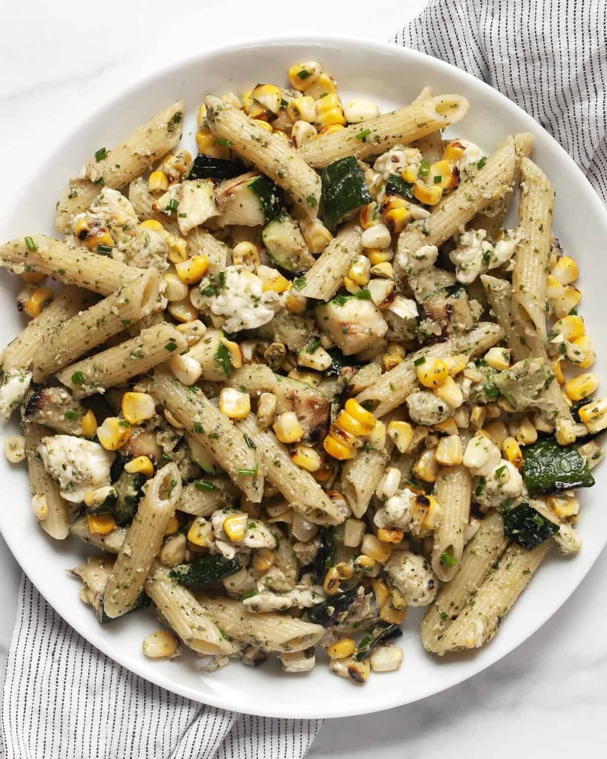 Grilled zucchini corn pasta with mint pesto on a plate.
