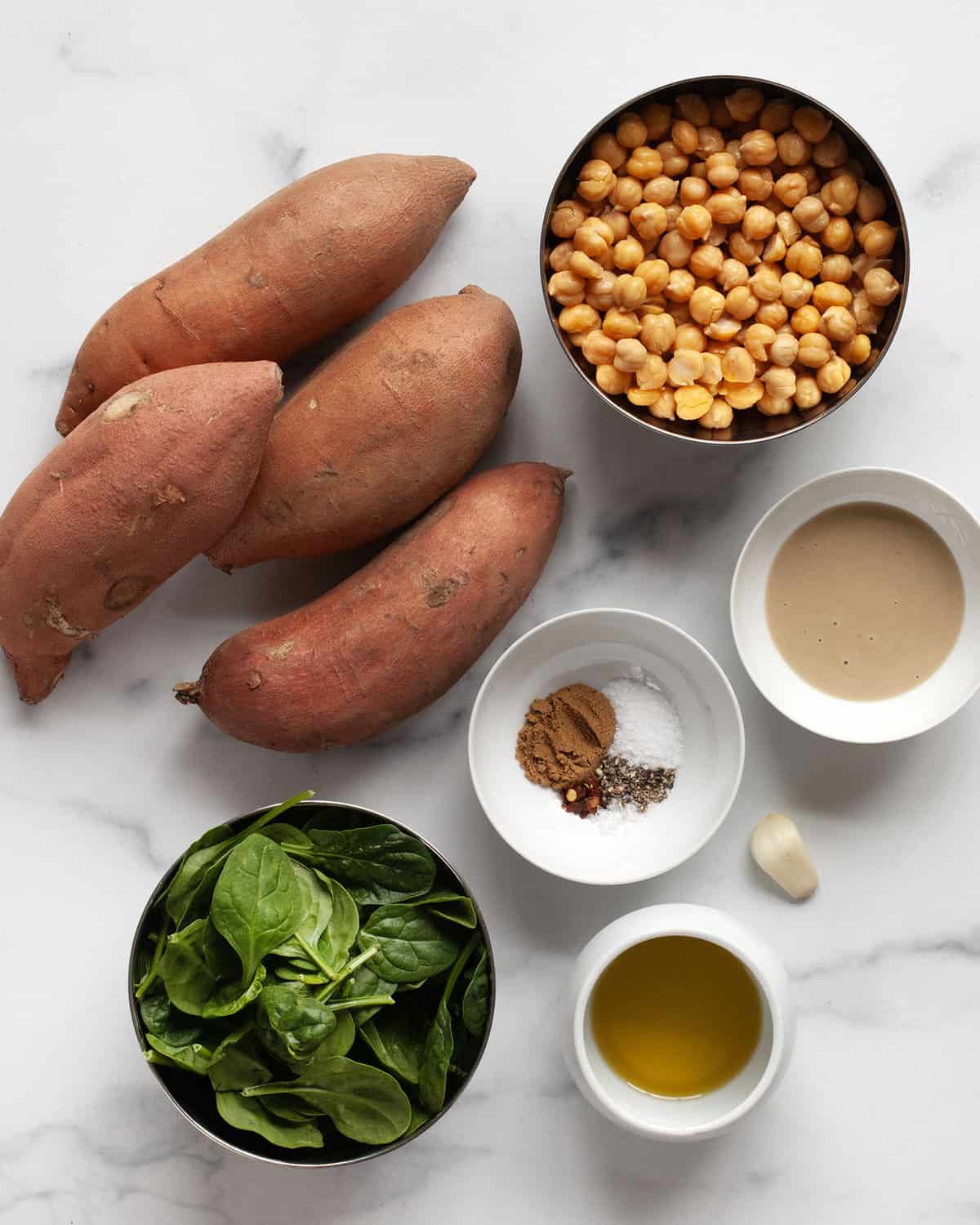 Ingredients including sweet potatoes, chickpeas, spinach, tahini, garlic, oil and spices. 