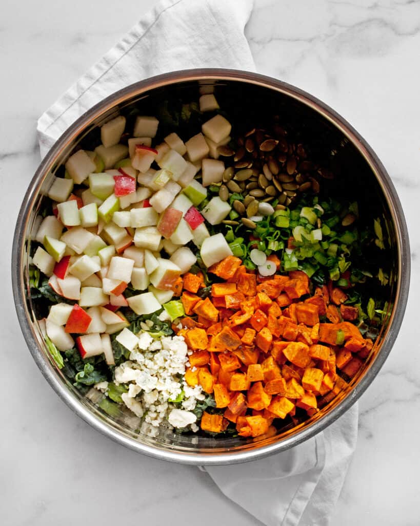 Combining the salad ingredients including apples, pears and sweet potatoes