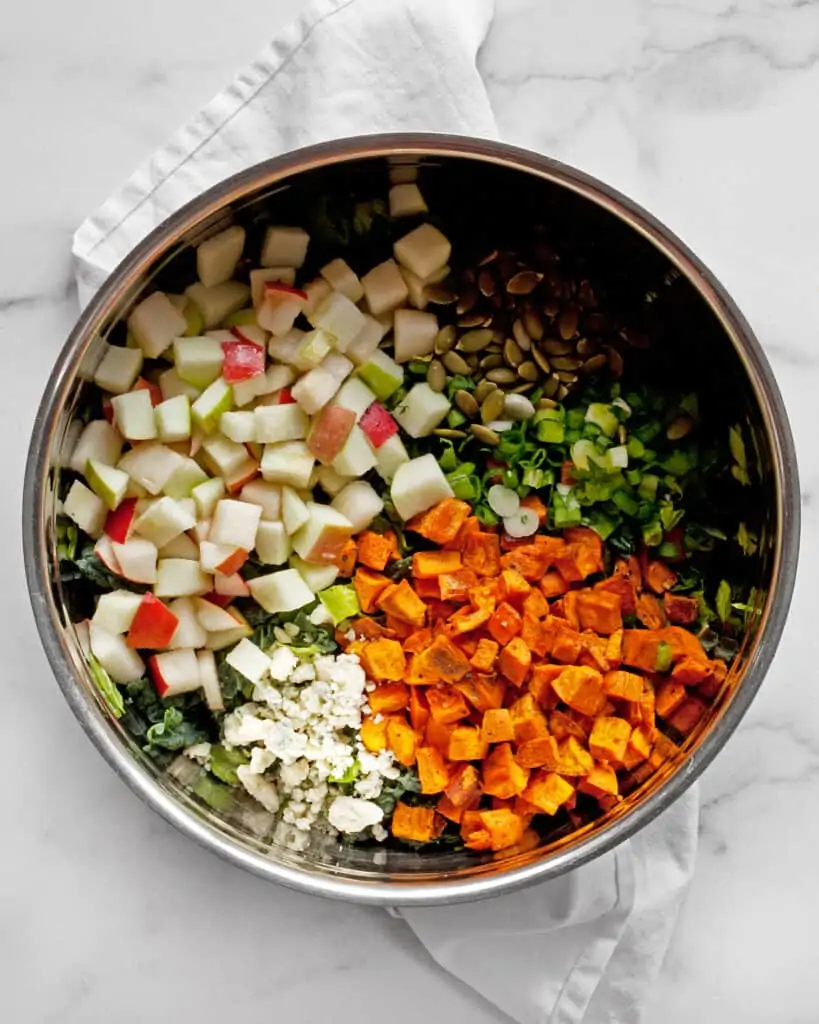 Combining the salad ingredients including apples, pears and sweet potatoes