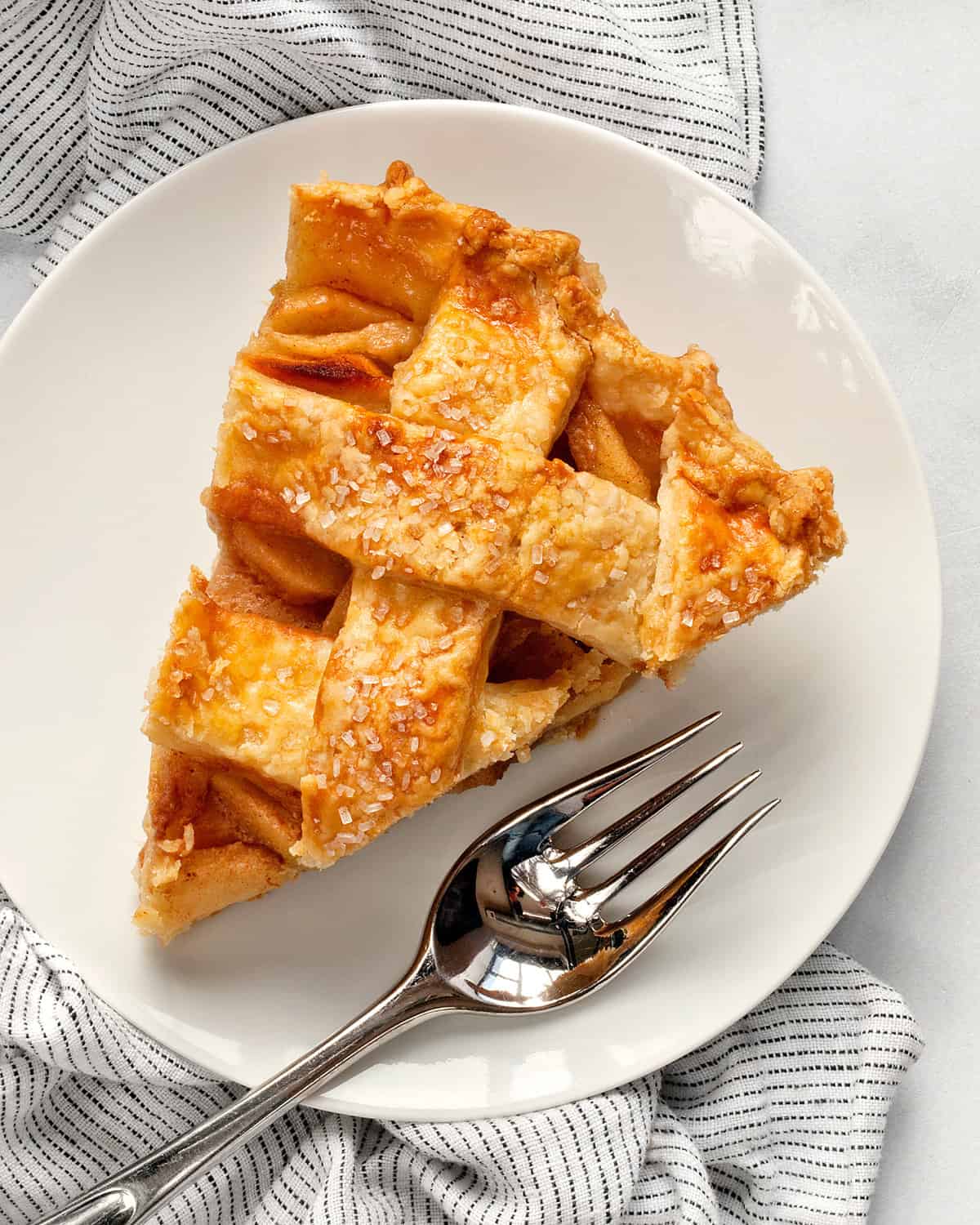 Slice of lattice apple pie on a plate.