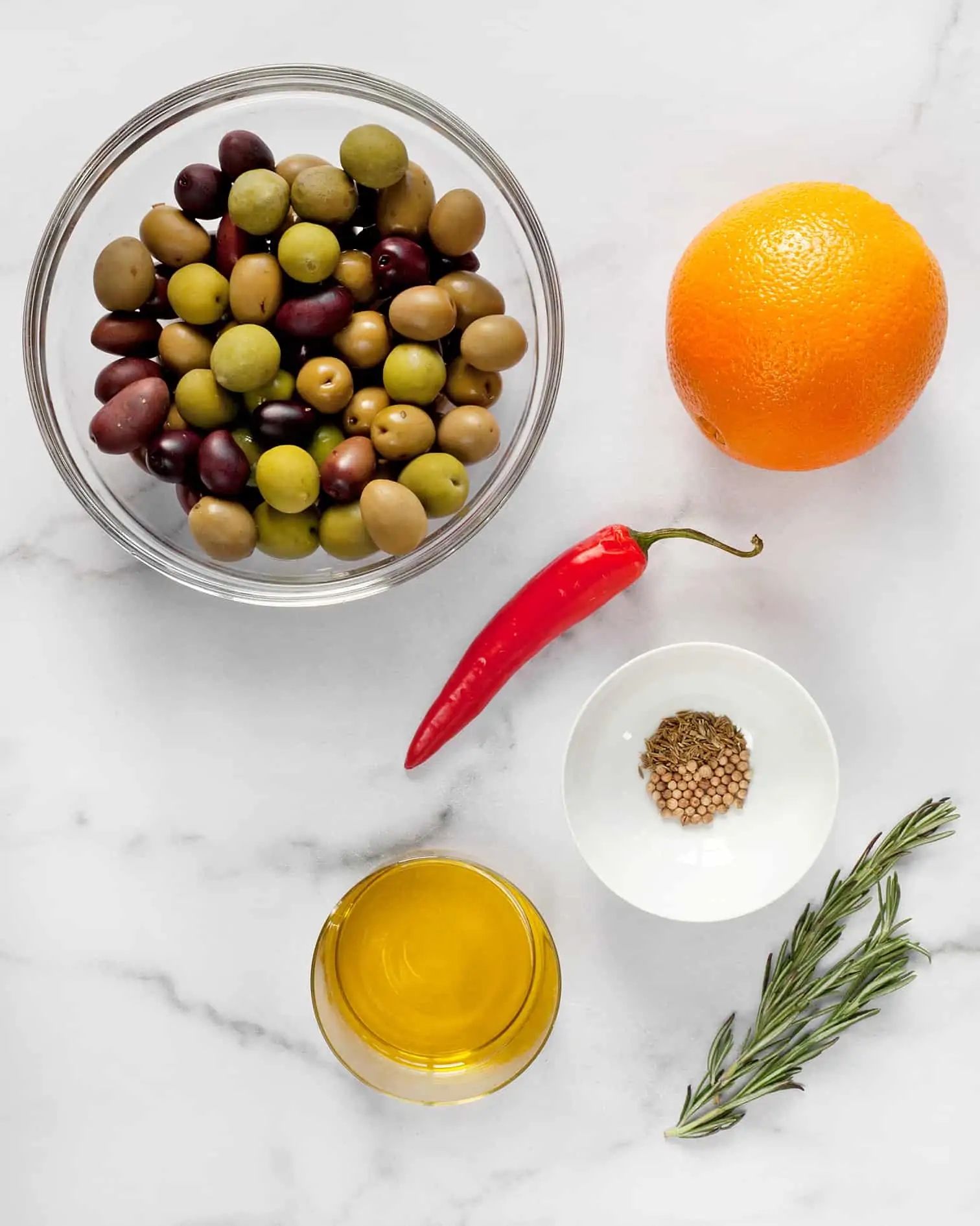 Ingredients including olives, orange, red chili, spices, rosemary and olive oil