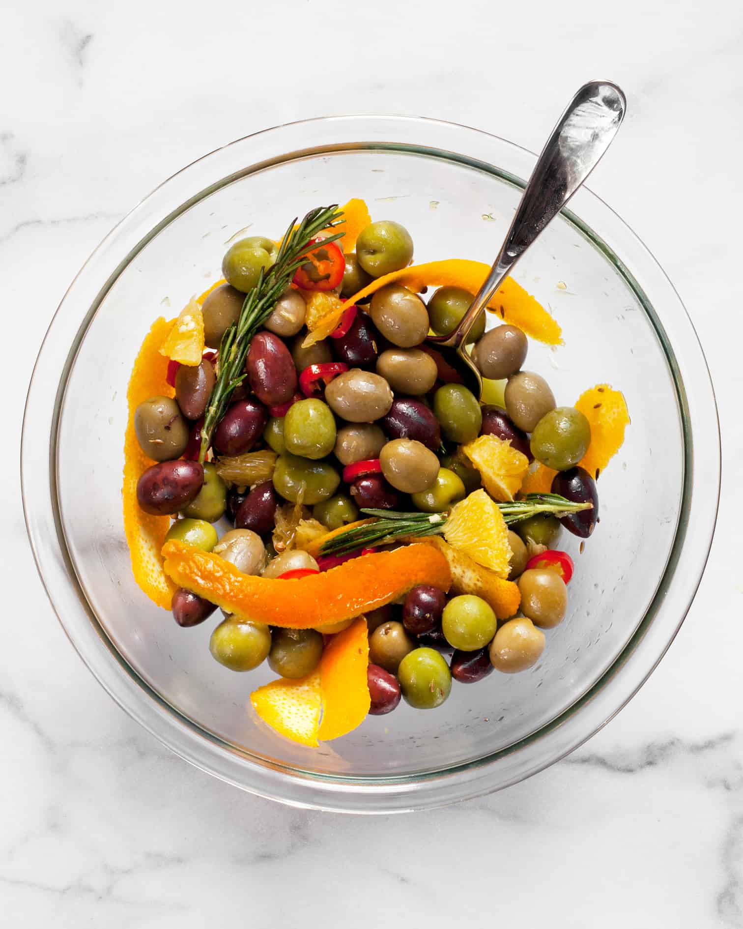 Combine teh olives, oranges, olive oil, chilies and spices in a bowl