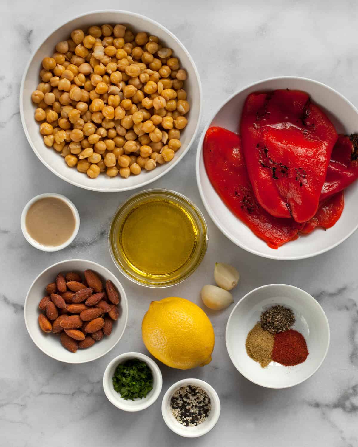 Ingredients including roasted red peppers, chickpeas, smoked almonds, lemon, tahini, olive oil and spices.