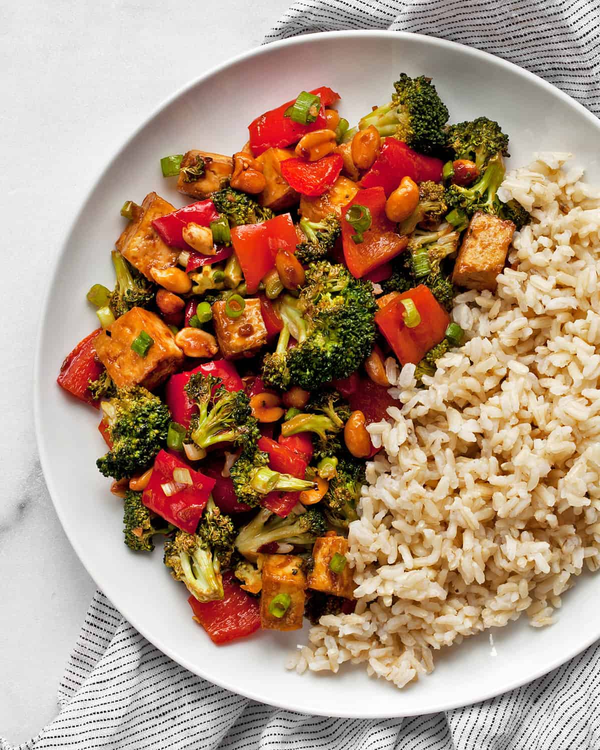 Kung pao tofu with brown rice on a plate.