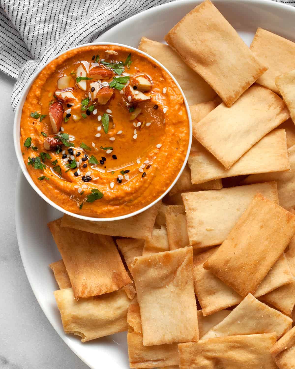 Roasted red pepper hummus in a bowl with pita chips.