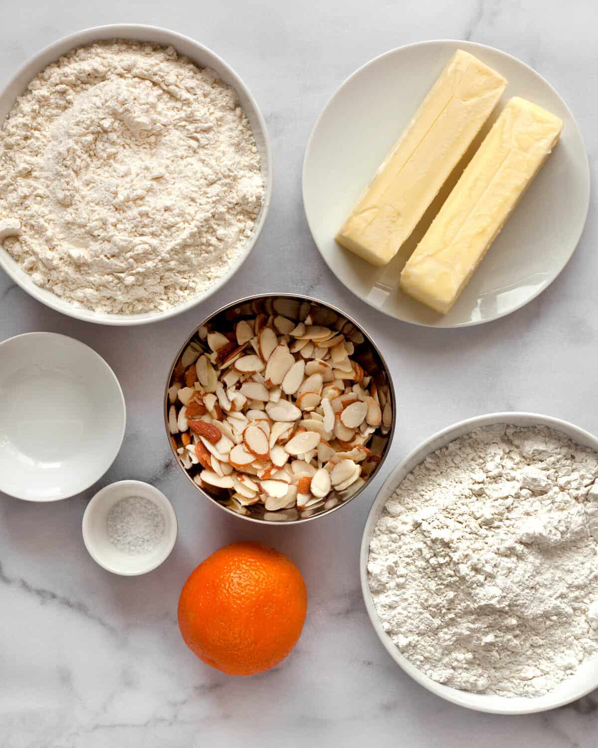 Ingredients including, flour, butter, powdered sugar, almonds, almond extract, and orange.