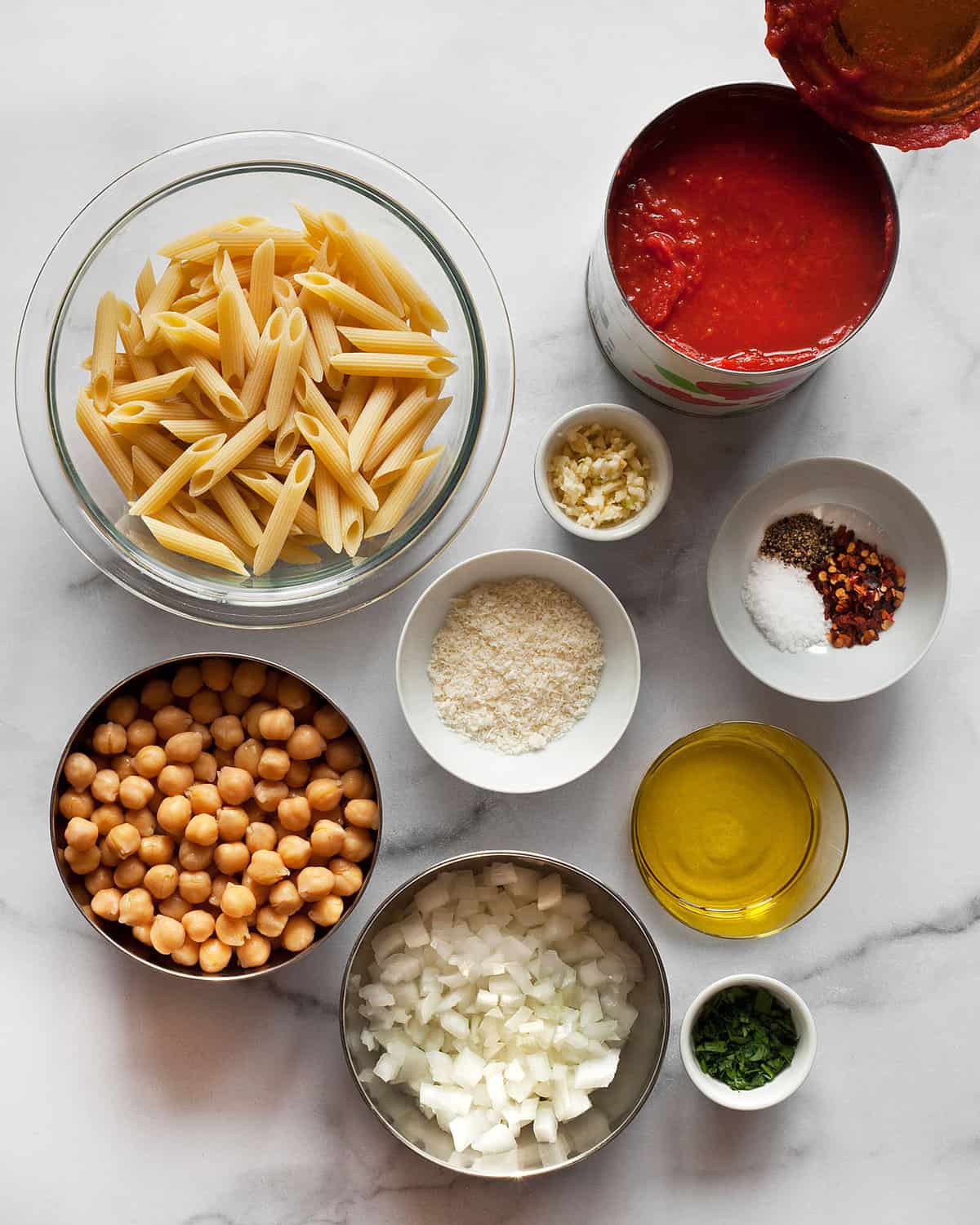 Ingredients including penne, chickpeas, canned tomatoes, garlic, olive oil and spices.