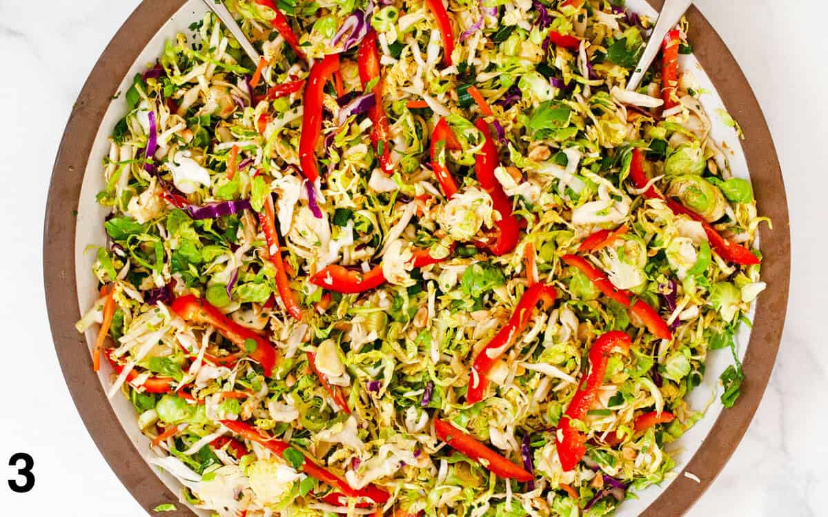 Salad ingredients tossed with dressing in a large bowl.