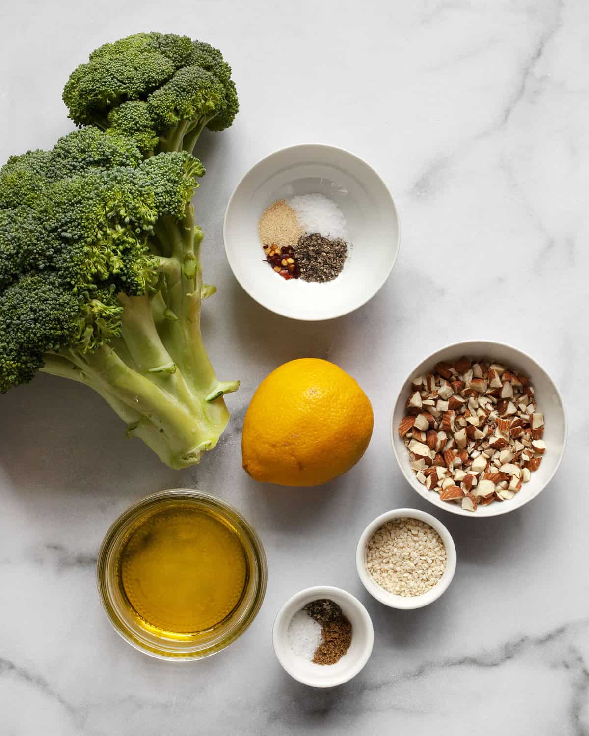 Ingredients including broccoli, lemon, olive oil, almonds, sesame seeds and spices.