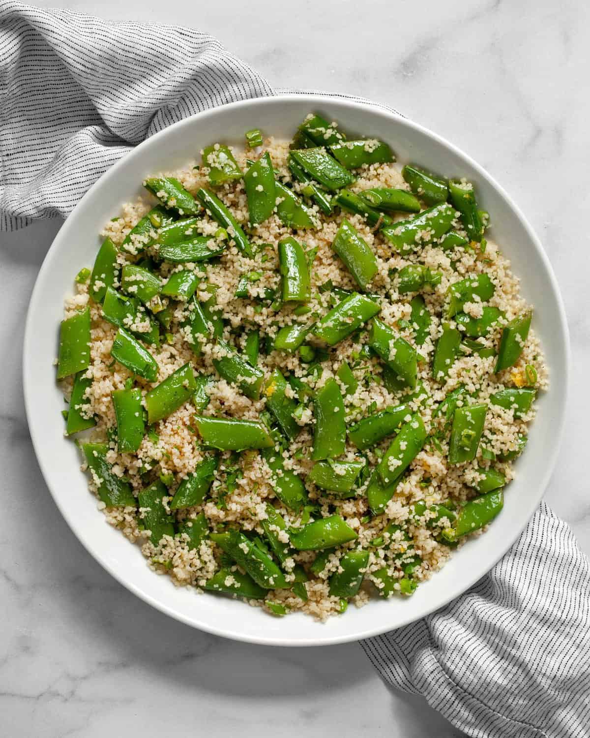 Couscous with snap peas on a plate.