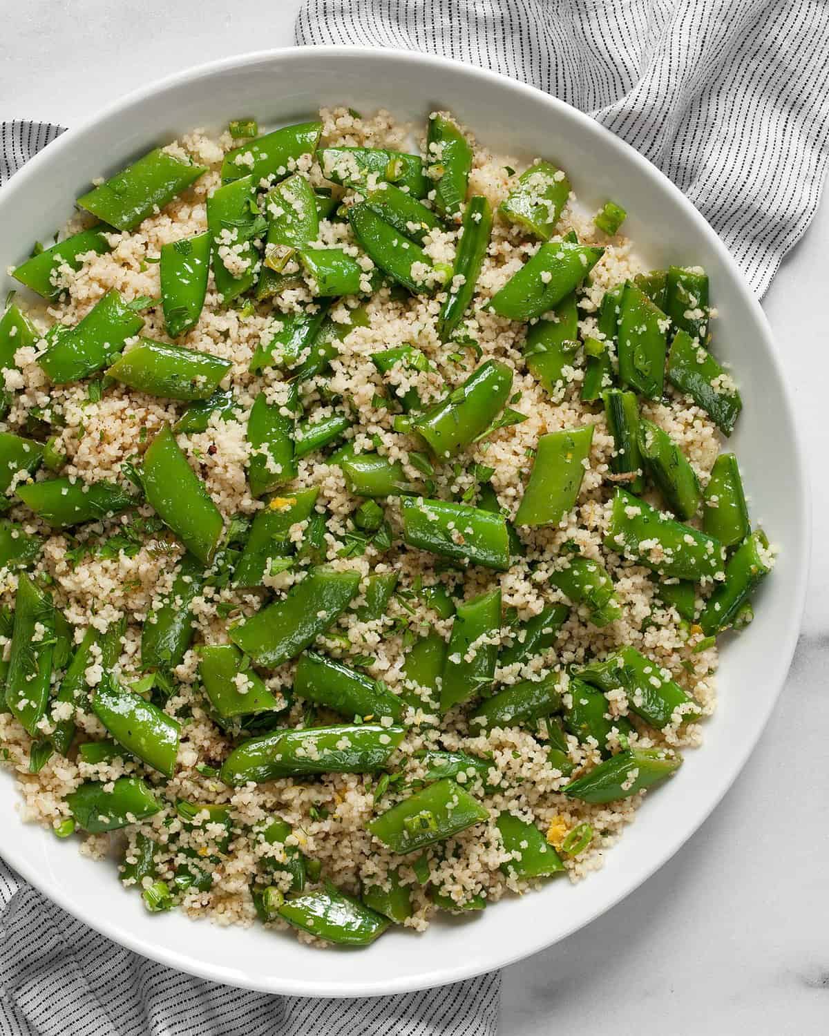 Couscous with snap peas on a plate.