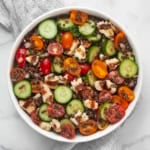 Lentil salad with grilled halloumi, cucumbers and tomatoes in a large bowl.