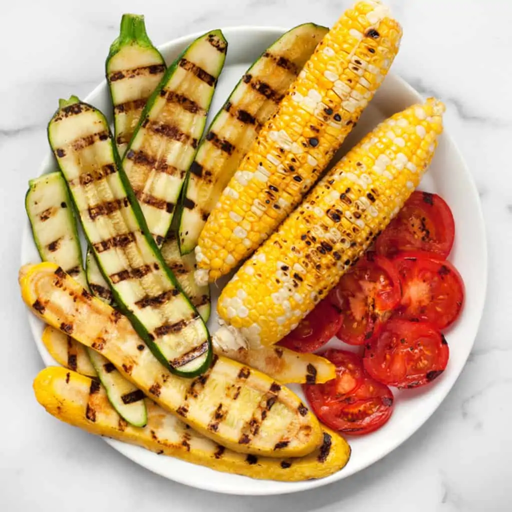 Grilled zucchini, squash, corn and tomatoes on a plate