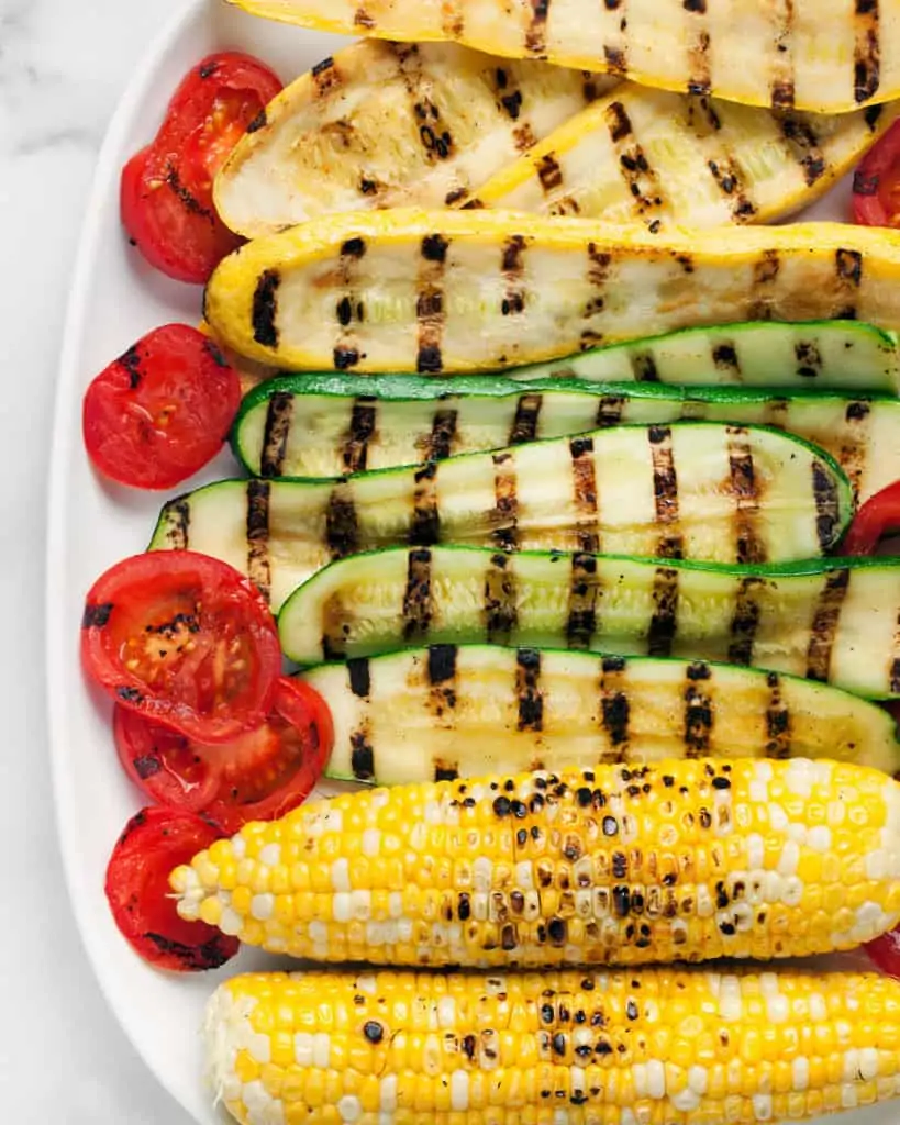 Grilled zucchini, squash, corn and tomatoes on a plate