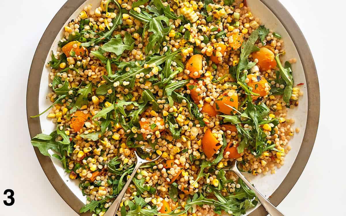 Summer couscous ingredients tossed together in a large bowl.