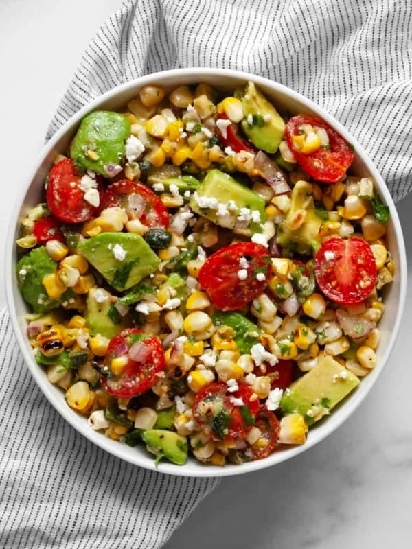 Corn salad with avocados and tomatoes in a bowl.
