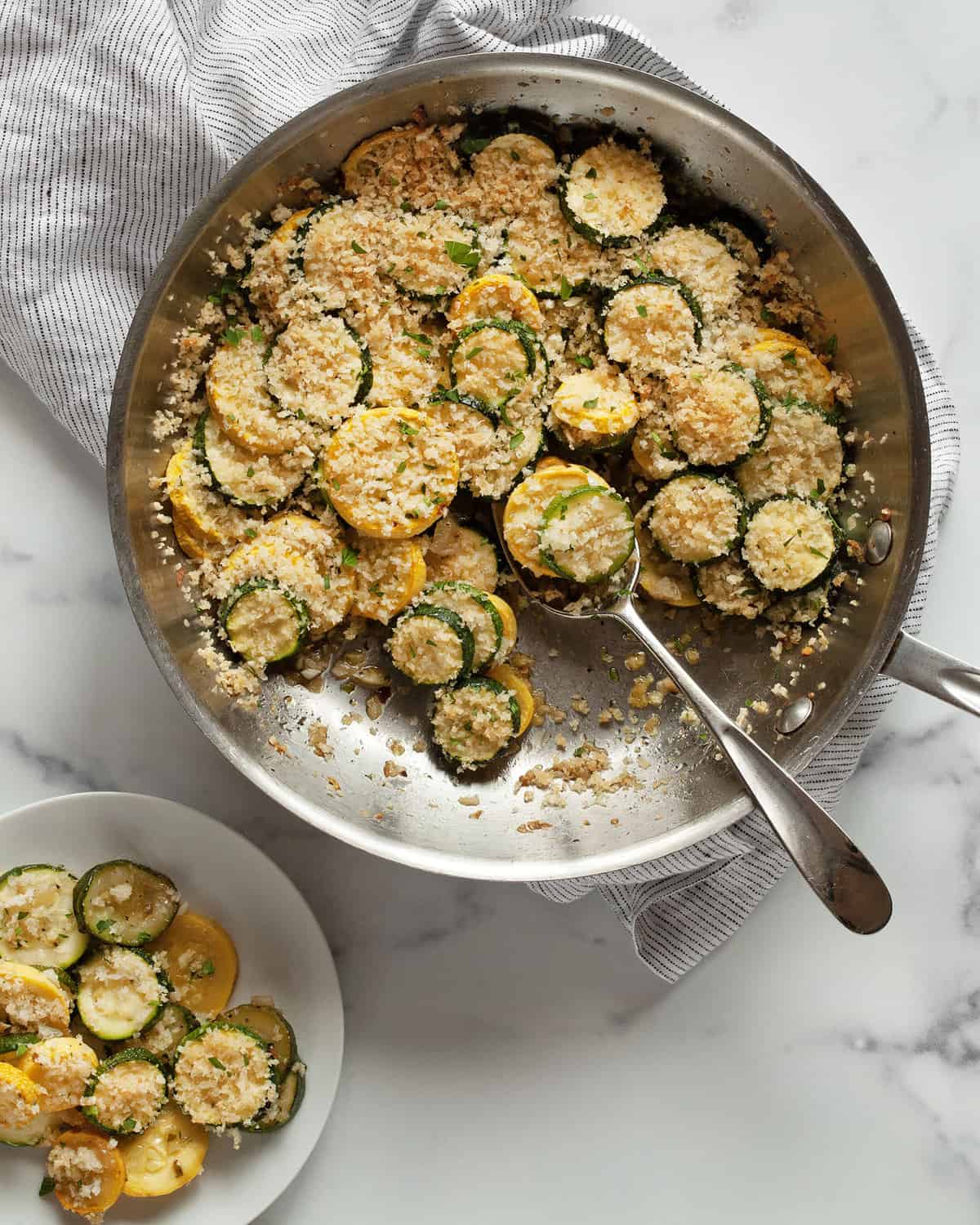 Spooning out squash casserole from the skillet onto a small plate.