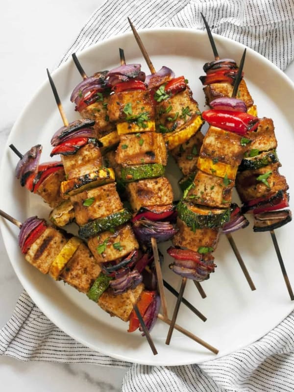 BBQ tofu veggie skewers stacked on a plate.