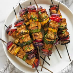 BBQ tofu veggie skewers stacked on a plate.