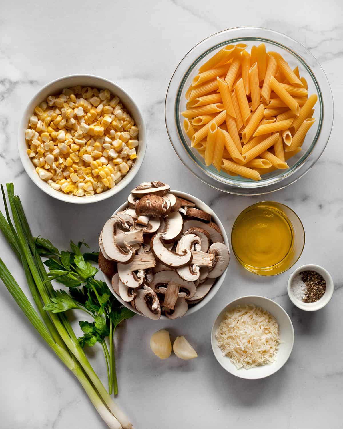 Ingredients including mushrooms, corn, penne, garlic, scallions, parmesan and parsley.