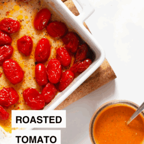 Roasted tomatoes in a baking dish with a jar of tomato vinaigrette next to it.